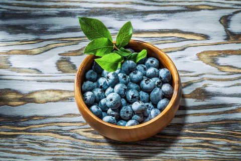 Ripe huckleberries in wooden bowl top view