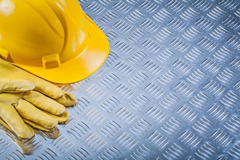 Protective leather gloves building helmet on channeled metal sheet construction concept