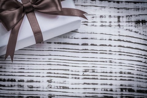 Wrapped present box red ribbon on vintage wooden board
