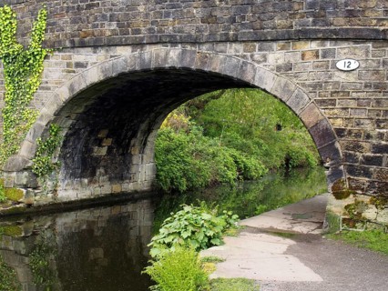 An old stone bridge crossing the rochdale canal at mytholmroyd west yorkshire with a waterside