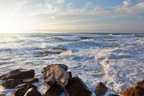 Magnificent sunset on Mediterranean sea. Storm waves break about breakwater stones on quay. Tel