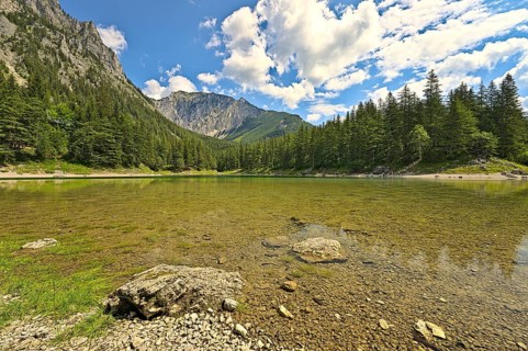 Green Lake in Styria during a summer day with people walking around the waterside