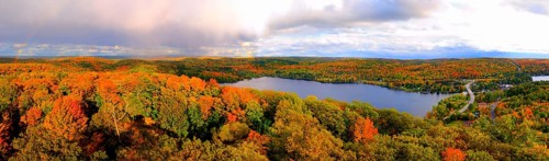 Aerial panoramic view of Lake of Bays and colorful fall forest during sunset with a trace of a