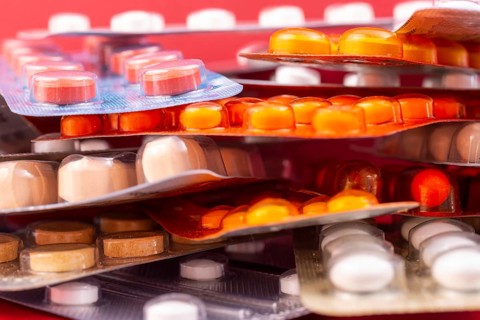Different colorful capsules and pills in plastic packs - blisters stacked. Global pharmaceutical