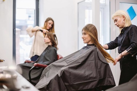 Beautiful woman combing wet hair. stylist brushing woman hair in salon. Hairdresser Serving