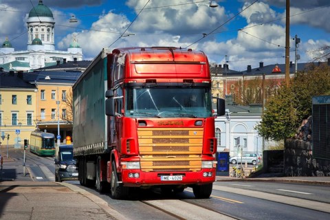 Red and gold 4-series Scania truck pulling semi trailer to Katajanokka Harbour. On the background