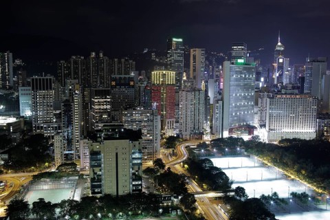 Illuminated Hong Kong. Night city view with concrete jungle, road interchange and football fields