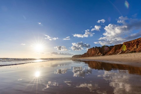 The golden sandy beach of Praia da Falésia, crystal clear sea water at low tide with the reflection