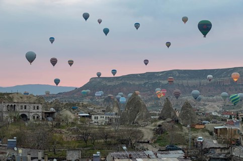 A picture of hot air balloons flying over the Goreme Historical National Park and the town of