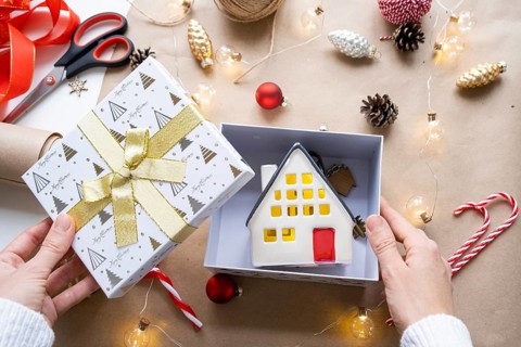 Key to house with keychain on cozy home in gift box with Christmas decor packaging. Pack present