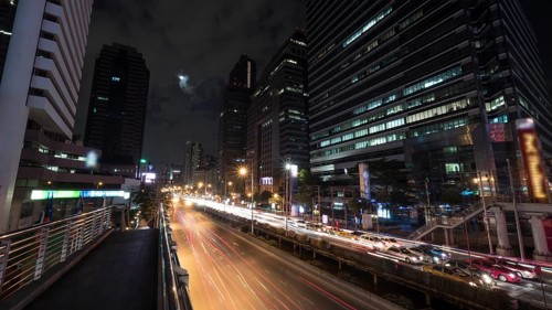 Timelapse shot of night Bangkok street. Intense transport traffic on the road with highrise