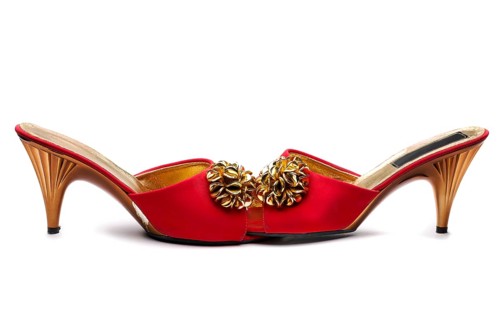 Pair red female shoe with gold brooch. Isolate on white