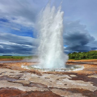 Iceland in the summer. Gushing geyser Strokkur. High column of hot water and steam from the crater