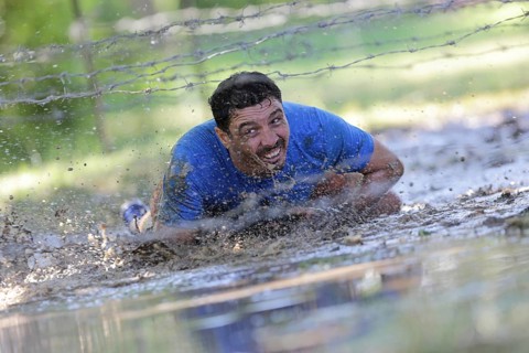 Sofia, Bulgaria - July 9, 2016: A participant is crawling through water under electrified wires at