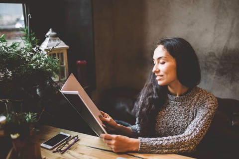 Young business girl studying the menu in restaurant decorated with Christmas decor.sits near the