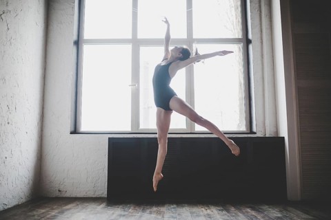 Plasticity slim woman dancing near window. Professional dancer enjoy dance. Lady Dancer Training