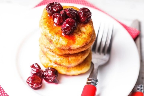 Cheese pancakes with cherry jam on the plate