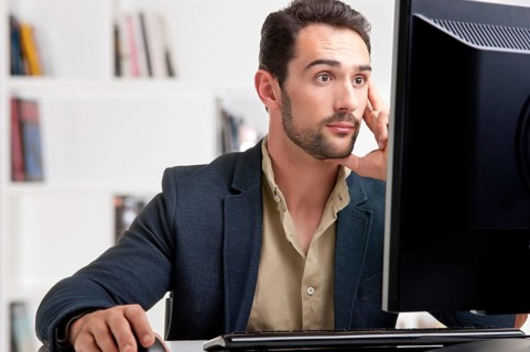 Surprised man looking at a computer screen, thinking about the job at hand