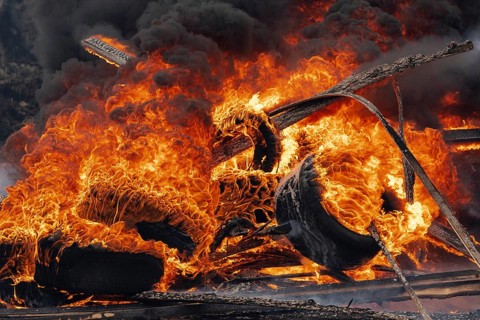 Burning automobile tires, strong flame of red fire and clouds of black fumes in sky. Selective