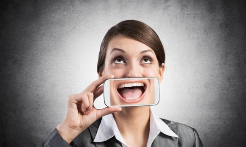Portrait of young woman covering her mouth with smartphone. Businesswoman showing mobile phone with