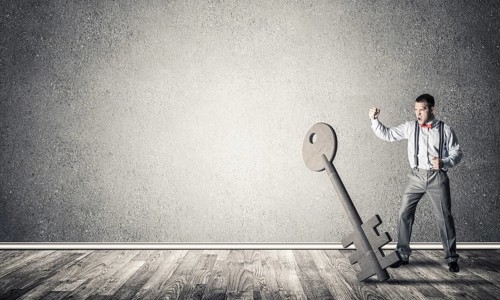 Determined businessman in concrete interior breaking with fist stone key figure