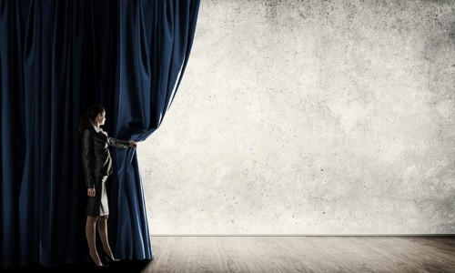 Young woman with megaphone in business suit opening color curtain