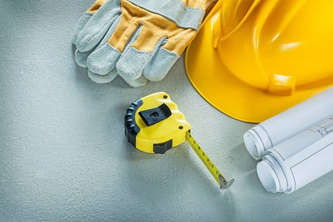 Set of blueprints building helmet protective gloves measuring tape on concrete background
