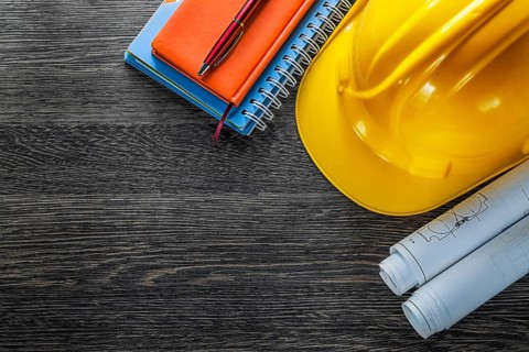 Construction drawings building helmet notepads pen on wood board