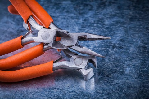 Set of insulated electric pliers nippers on scratched metallic background