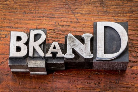 Brand word in vintage metal type printing blocks over grunge wood, mixed fonts in style and size