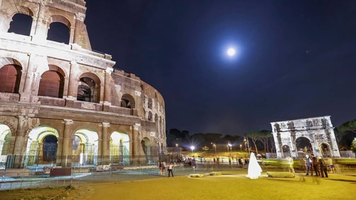Roman Colosseum and Constantine Arch by night with tourists and photographers with a bride for