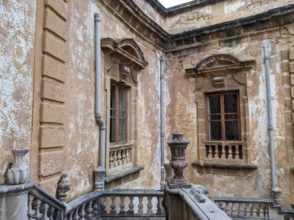 Weathered walls and ornate architectural details with classical windows and stone railing, Villa