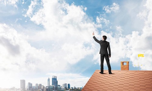 Businessman on house roof touch empty space. Mixed media