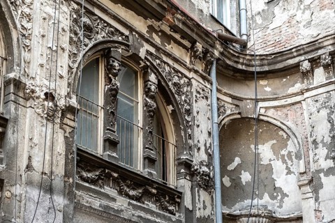 Dilapidated old building façade with stucco and ornaments
