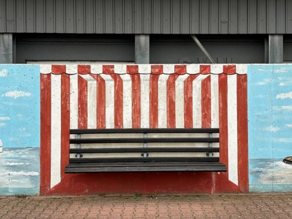 Bench with mural on a wall in the harbour, depicting a beach chair, Norderney