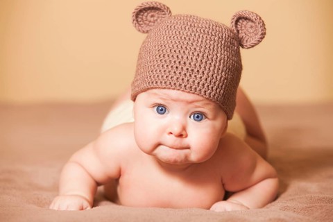 Adorable baby in bear hat lying on the bed