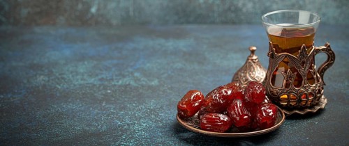 Breaking fasting with dried dates during Ramadan Kareem, Iftar meal with dates and Arab tea in