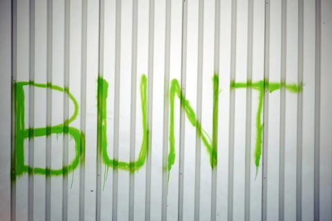 The detail of a corrugated iron façade colourfully painted with the slogan