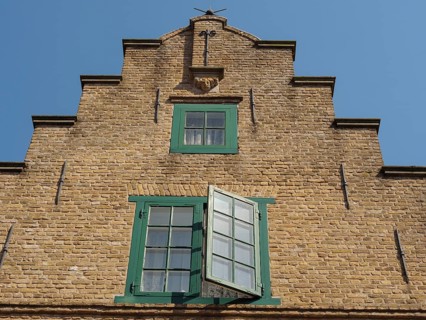 Historic brick building with green framed windows and blue sky, friedrichstadt, schleswig-holstein,