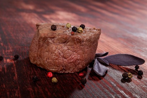 Luxurious sirloin steak on wooden background with peppercorn and herbs. Culinary red meat eating.