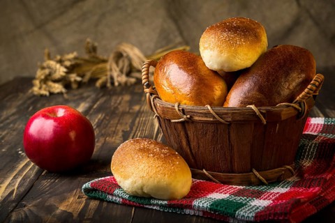 Baked apple pies in basket on wooden table