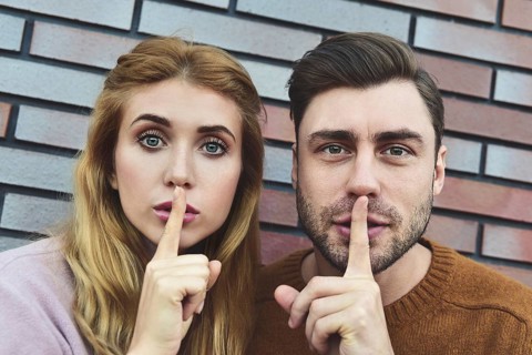 Attractive young Caucasian couple pretty woman and handsome man asking for silence, keeping index