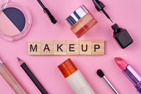 Close up of various female makeup accessories on pink background. Wooden cubes with text makeup