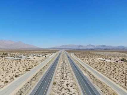 Aerial view of road in the middle of the desert under blue sky in California's Mojave desert, near