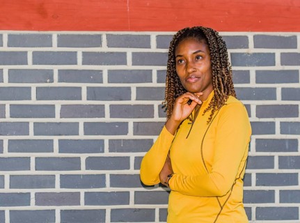 Young black woman in yellow with curly hair posing against a brick wall, Taken in Daejeon, South