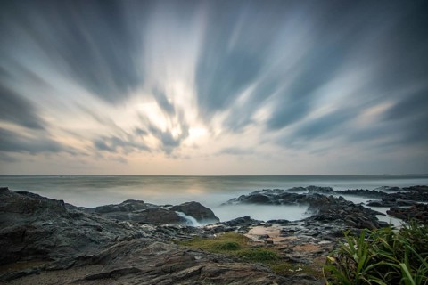 Beach, with lava rocks and vegetation, view of the sea in the evening at sunset. Landscape with