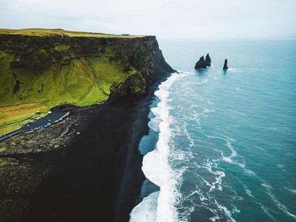 Volcanic Black Sand Beach with a view of Reynisdrangar. Waves crashing on the black sand beach.
