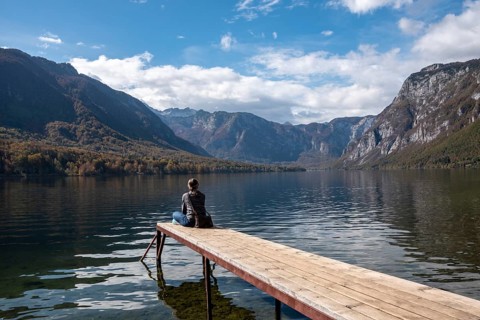 Sitting on a small jetty and enjoying the view on the landscape of lake Bohinj in the Triglav