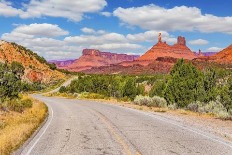 The reds and browns of Utah's vibrant landscapes. Wide asphalt highway among picturesque hills and