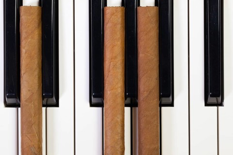 Detail of piano keyboard and luxury cigars